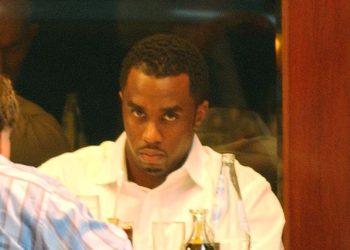 Man in a white shirt at a table with drinks, looking intently at the person across from him.