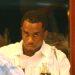 Man in a white shirt at a table with drinks, looking intently at the person across from him.