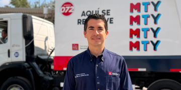 Man in a navy uniform standing in front of a branded delivery truck with MTY graphics in red and blue.