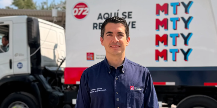 Man in a navy uniform standing in front of a branded delivery truck with MTY graphics in red and blue.